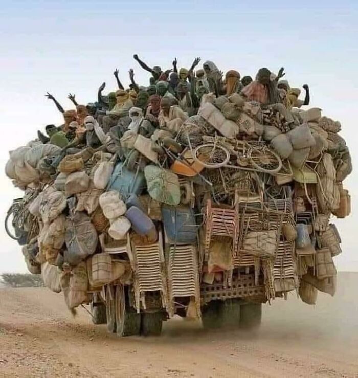 Overloaded truck carrying many people and belongings in a moving fails scene