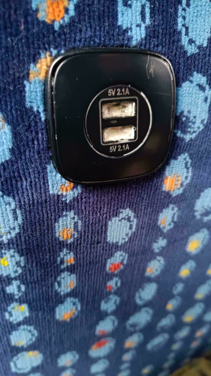 Close-up of damaged USB ports on a seat, showing a frustrating public transport interaction