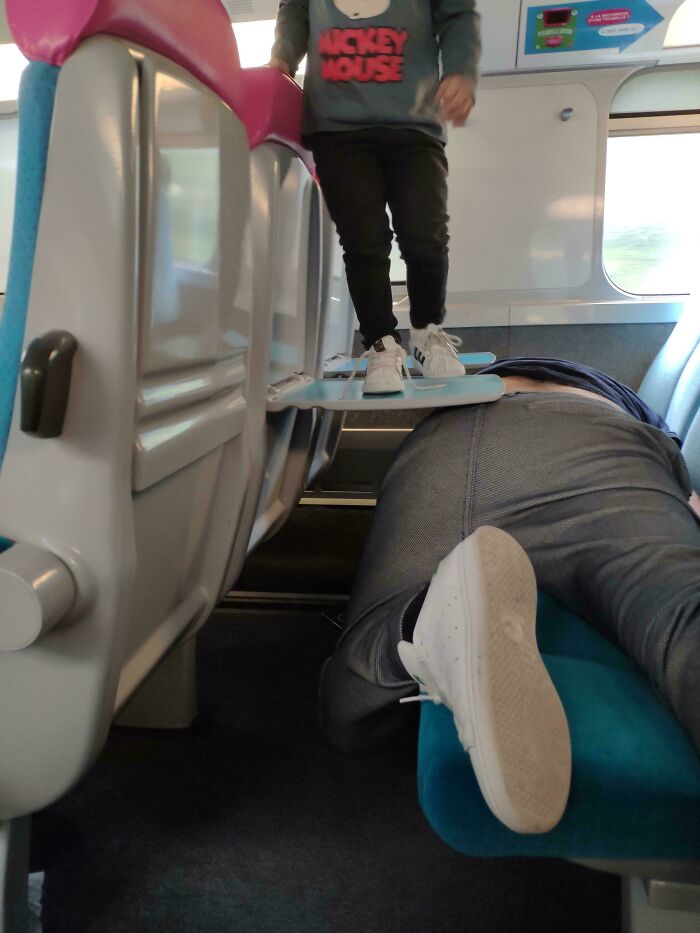 Wild public transport interactions of a child standing on a tray table while a passenger lies down