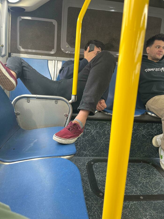 A passenger resting his dirty shoes on a bus seat, representing annoying public transport interactions.