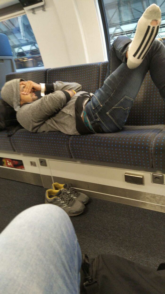 A passenger lying down across three train seats, exemplifying bad public transport interactions.