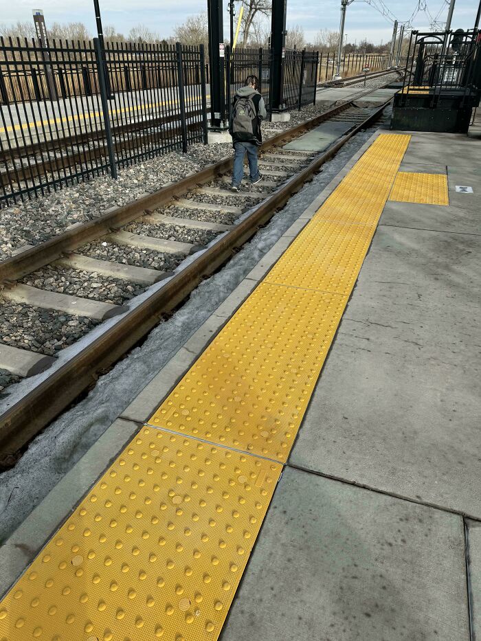 A person walking dangerously on train tracks, demonstrating risky public transport interactions