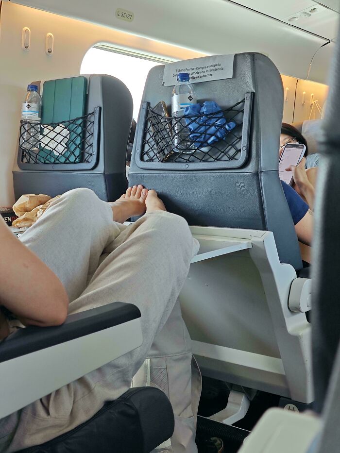 Passenger with bare feet resting on the seat headrest showing rude public transport interactions on a train