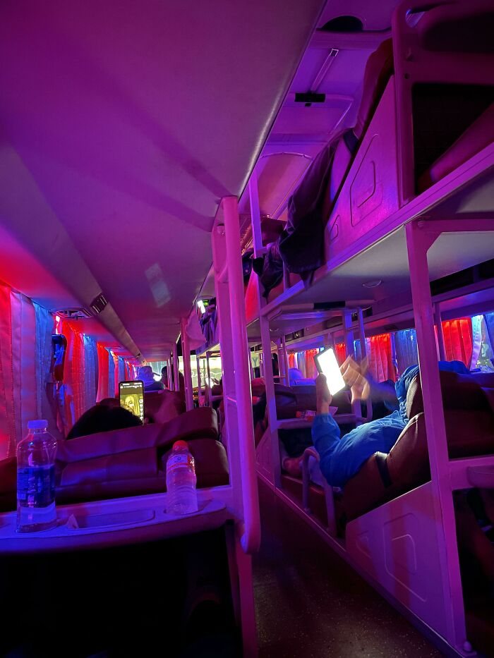 People on a sleeper bus with bright screens, highlighting public transport interactions.