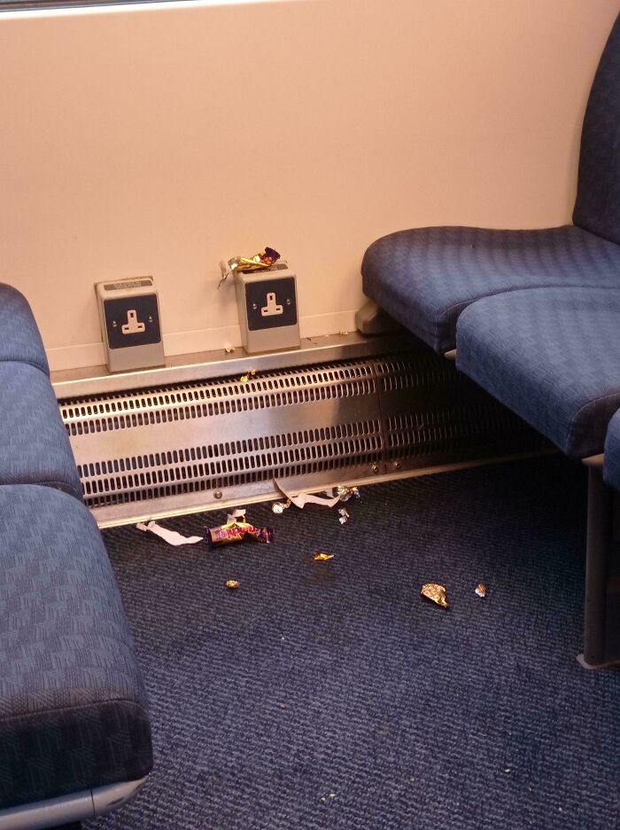 Trash and candy wrappers on a train floor, showing messy public transport interactions.