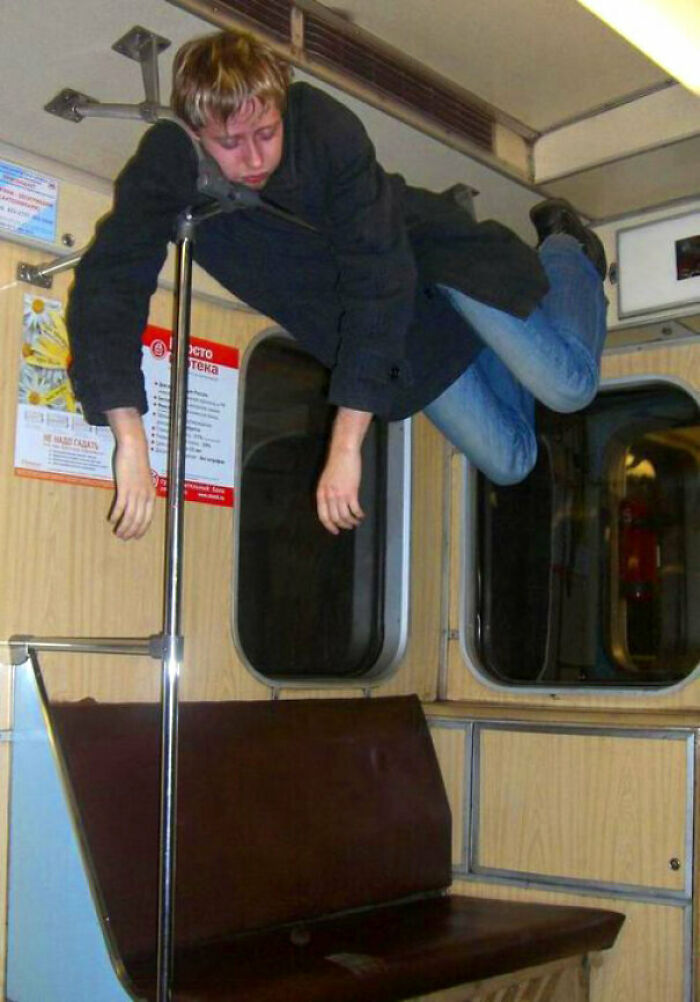 A passenger levitating horizontally between the handrails in a public transport subway car