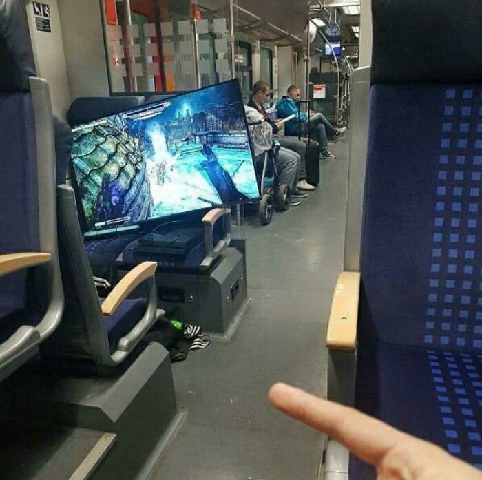 A full television and console gaming setup placed on a train seat, depicting public transport interactions.