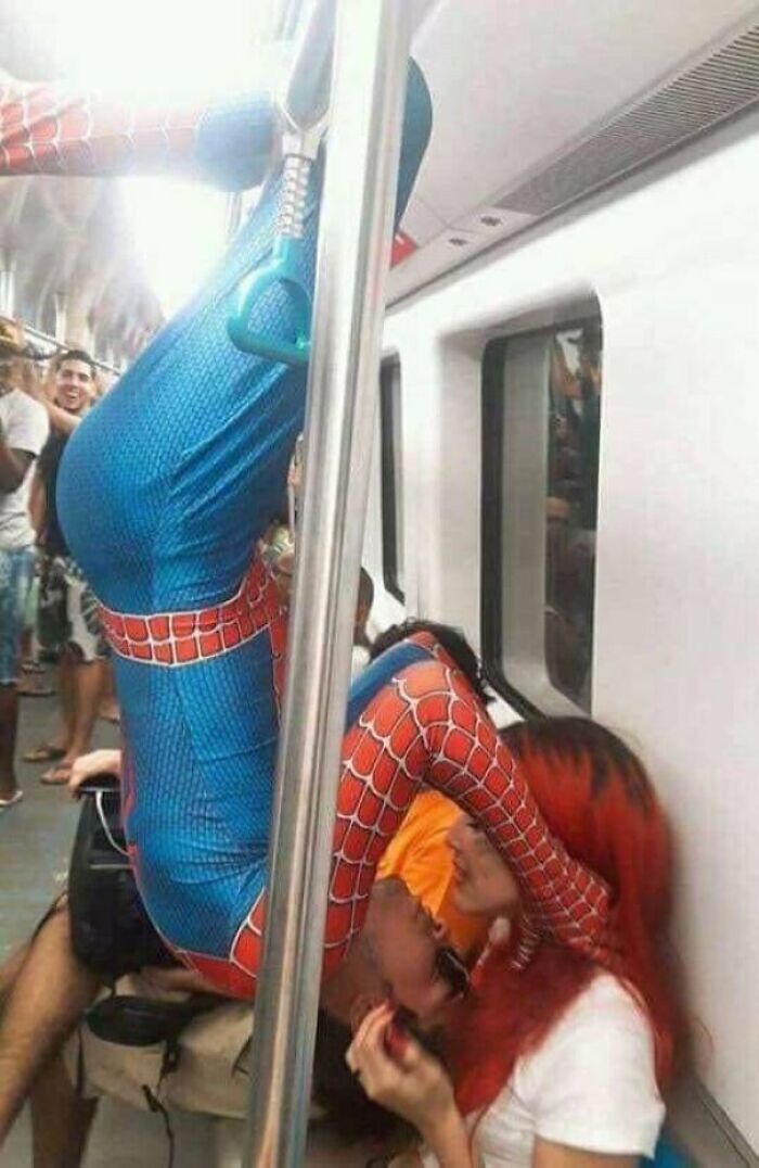 A person in a Spider-Man suit hanging upside down on a subway train, an example of public transport interactions.
