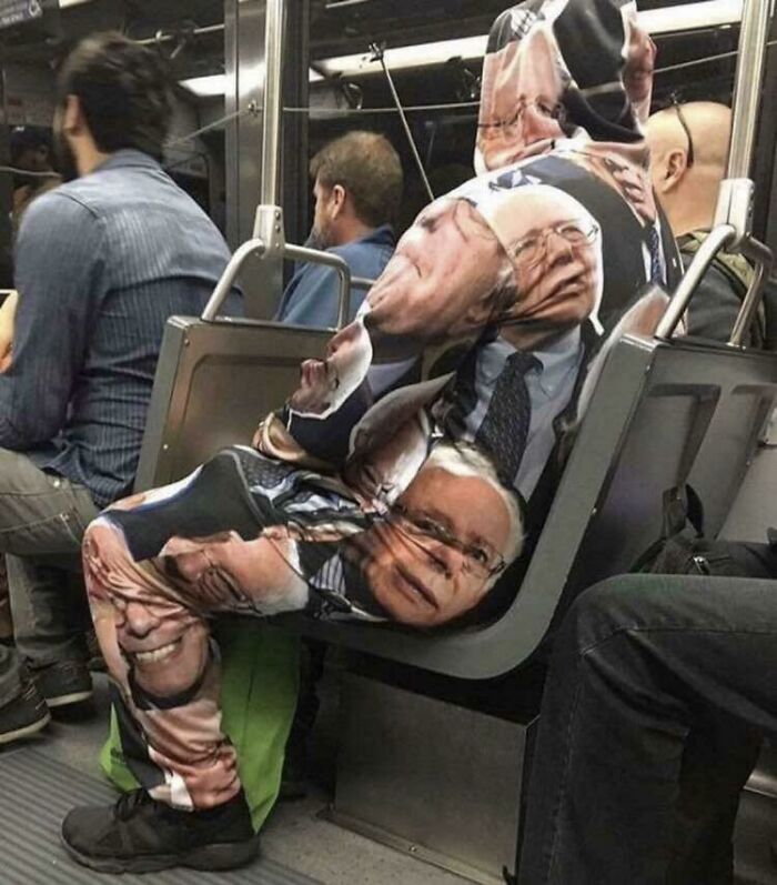 A person wearing a suit covered in Bernie Sanders faces on a train, illustrating public transport interactions.