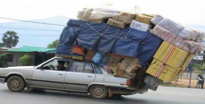 Car overloaded with moving boxes and furniture tipping backward on street