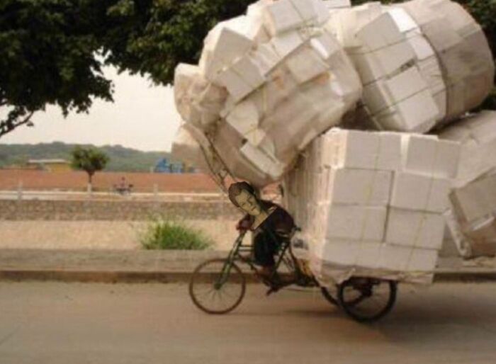 Man riding bike overloaded with huge foam blocks moving fails