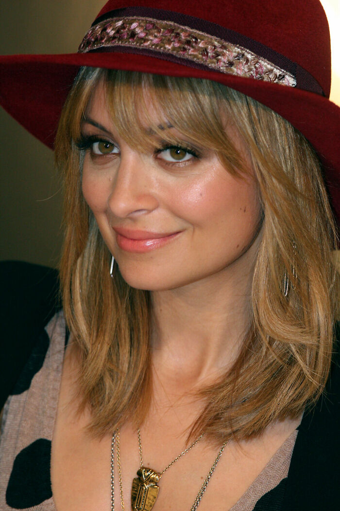 Nicole Richie smiling while wearing a stylish burgundy wide-brimmed hat