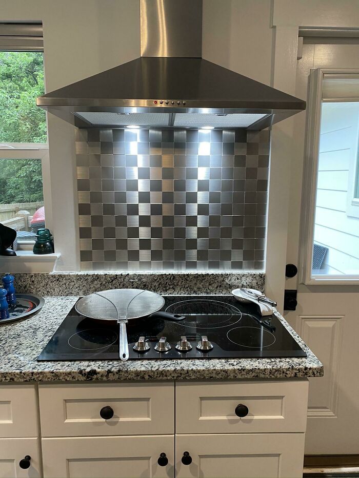 A stylish stainless steel tile kitchen backsplash with a modern range hood, a great DIY home upgrade idea.