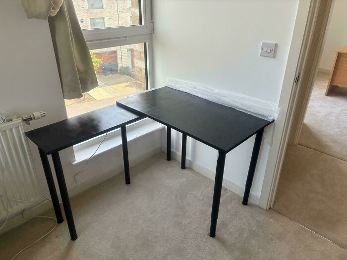A black corner desk placed by a window, ideal for DIY home upgrades