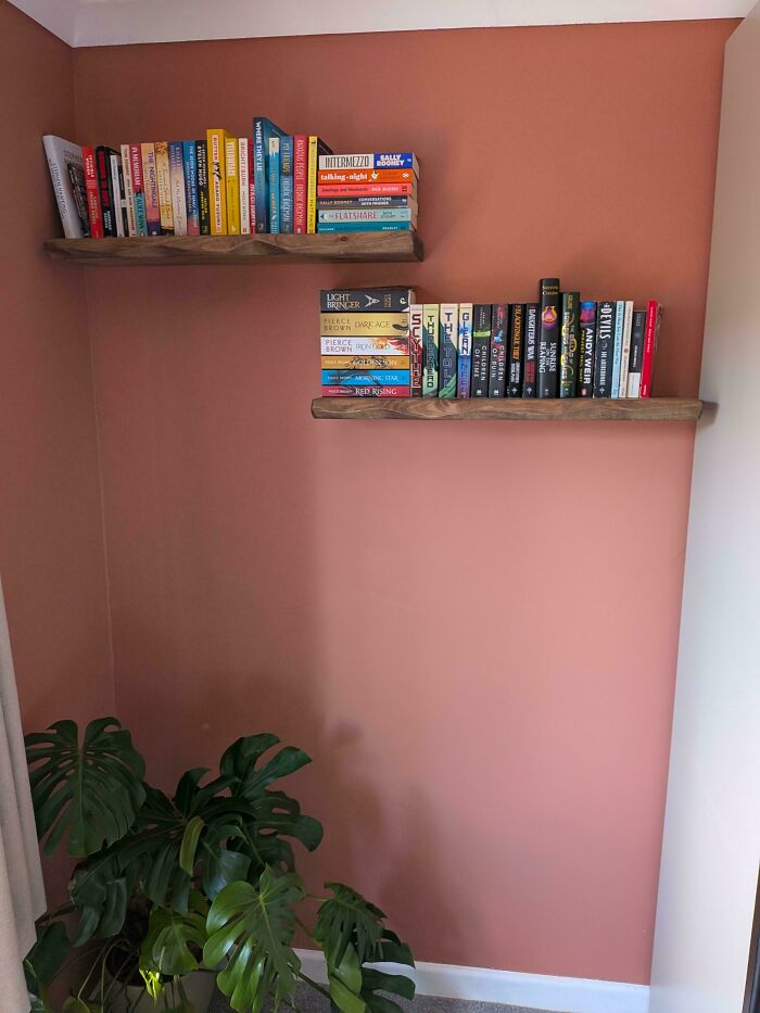 Floating wooden bookshelves installed as smart DIY home upgrades on a terracotta wall.