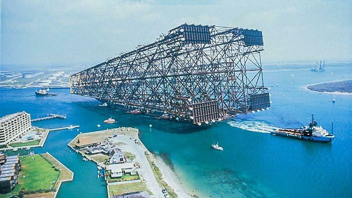 Massive industrial offshore infrastructure being transported on the water by tugboats