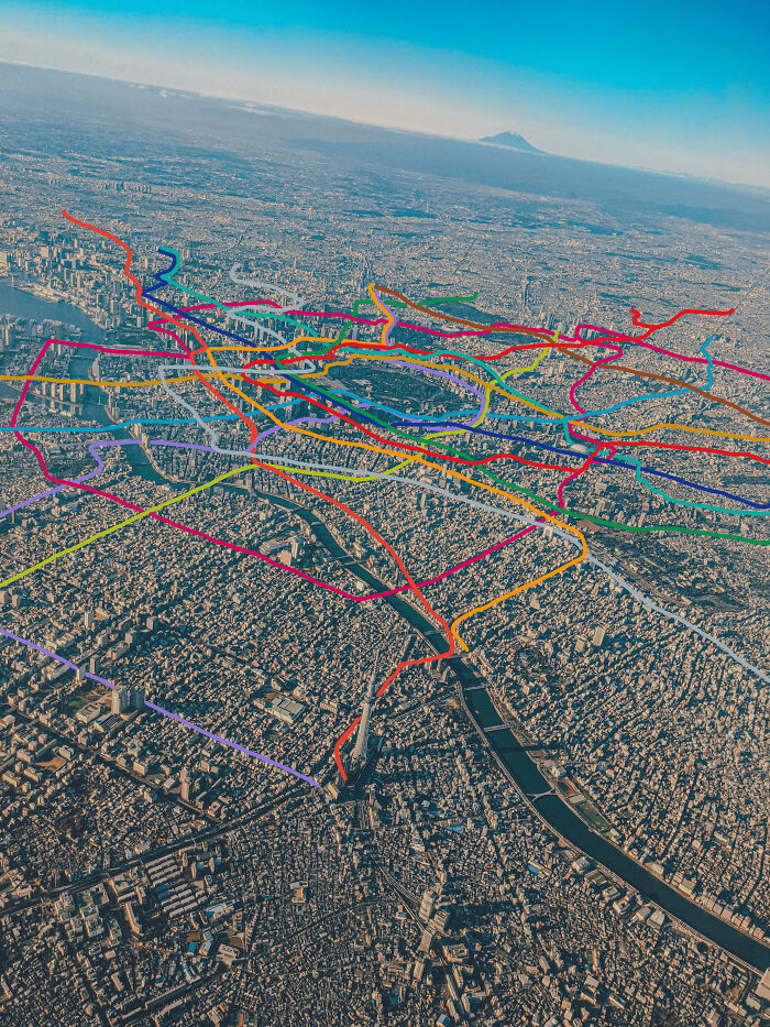 An aerial view of a vast metropolis overlayed with colorful transit lines showcasing transit best infrastructure.