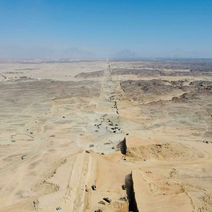 Aerial view of massive earthworks in a vast desert landscape showing major world infrastructure under construction