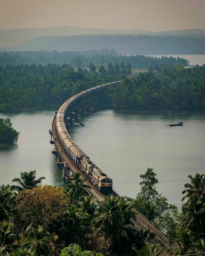 Long train on a curved bridge over water, highlighting scenic railway transport infrastructure