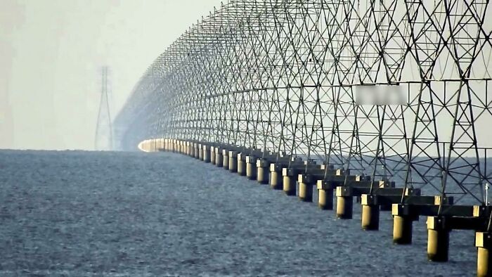 A long row of high-voltage power line towers stretching over water, showing world's best infrastructure