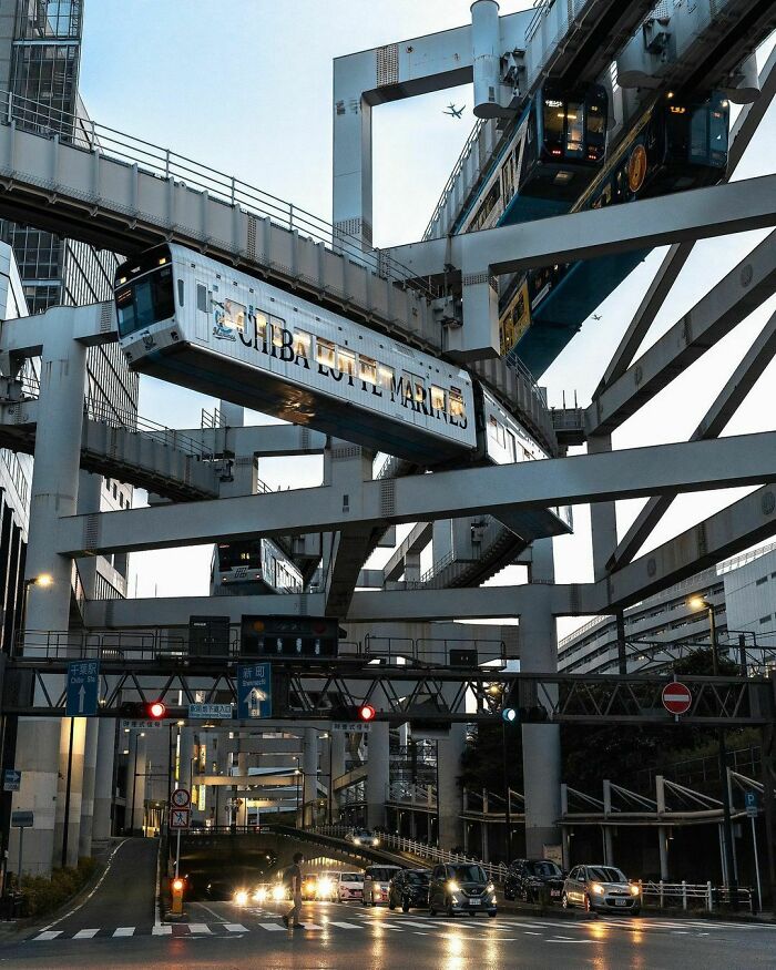 Futuristic suspended monorail trains operating above a busy city street, a high-tech example of urban infrastructure