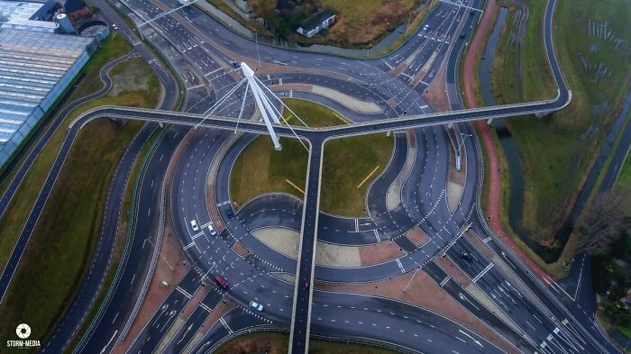 Aerial view of a unique circular highway junction and suspended pedestrian bridge, showcasing smart city infrastructure