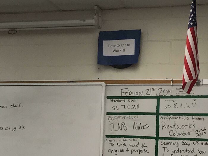 A classroom clock covered by a paper sign saying Time to get to Work, showing how teachers motivate students.