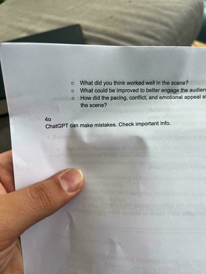 A hand holding a printed school worksheet that includes a ChatGPT warning notice, showing funny teachers