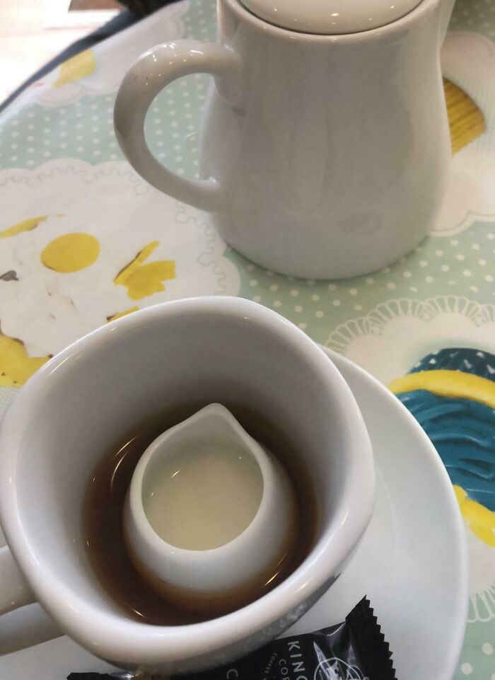 A white cup of tea with a smaller milk pitcher sitting inside it, making a funny British meme about making tea.