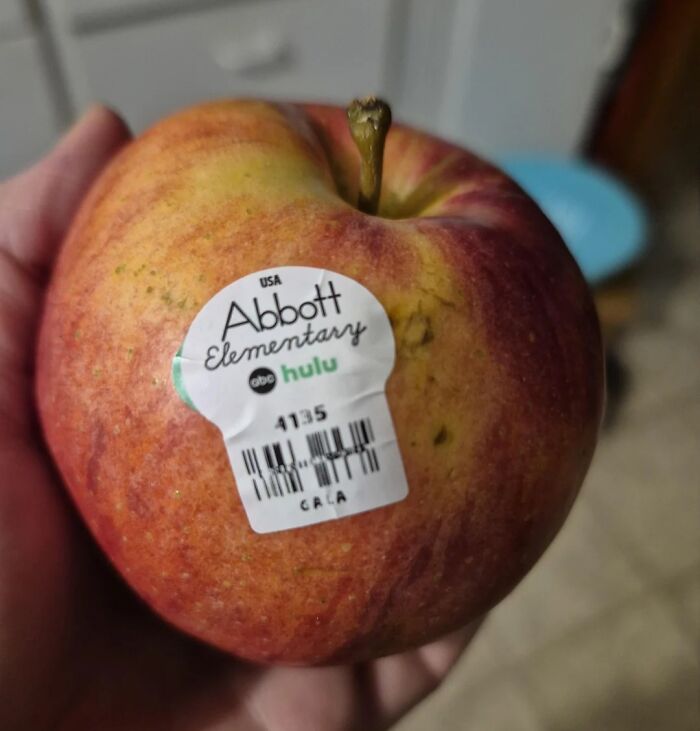 An apple with an advertising sticker on it showing a terrible product design that ruins the fruit