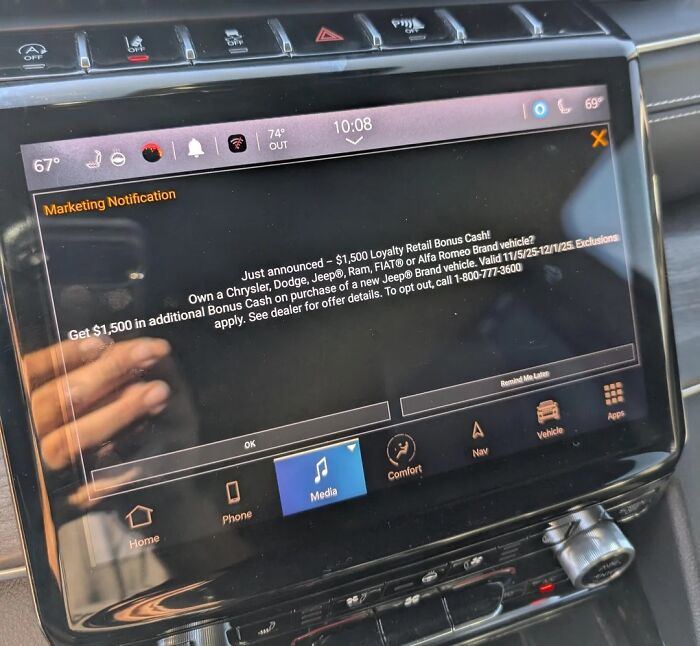 A car dashboard display showing an unwanted marketing notification as terrible product design.