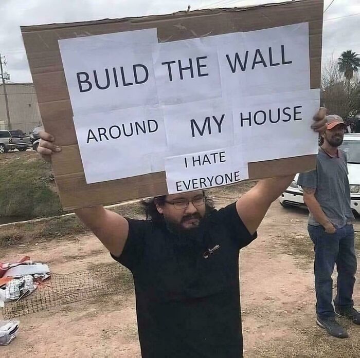 Unhinged protest sign demanding a wall around a house with a message of hating everyone