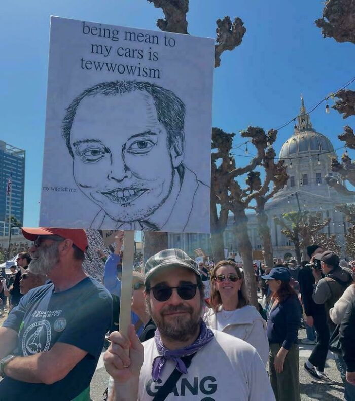 Protestor holding sign with caricature and joke about being mean to cars