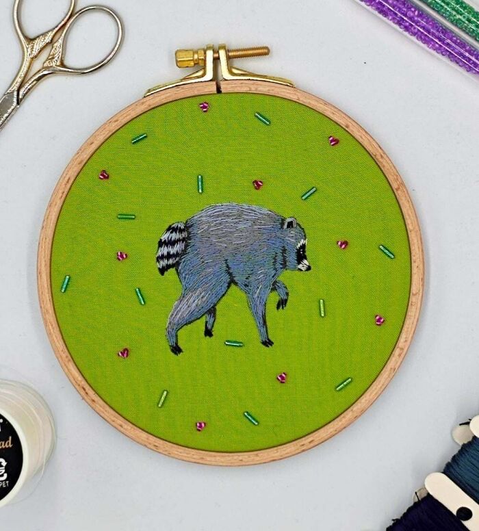 Handmade embroidery project showing a raccoon on bright green fabric