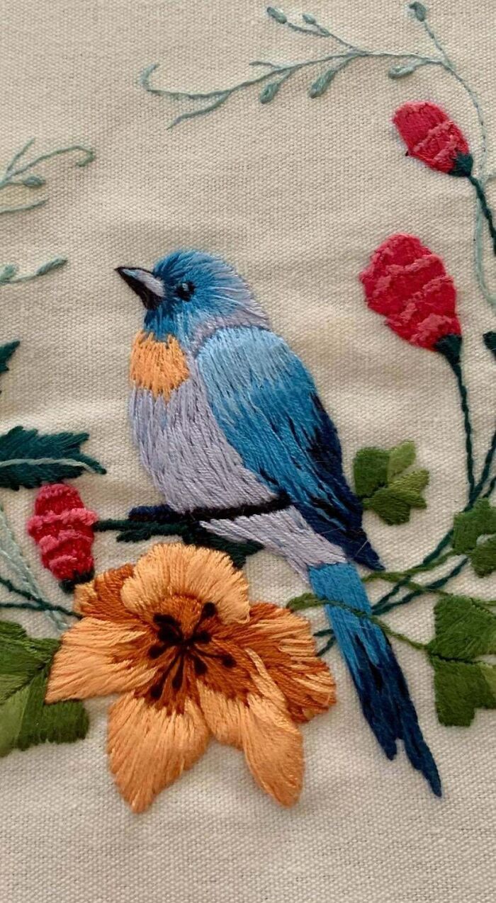 Detailed embroidery projects featuring a vibrant blue bird perched among colorful flowers.