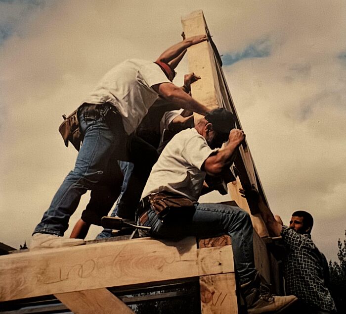 Construction workers raising a wooden frame in an Accidental Renaissance style scene