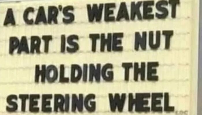 Humorous sign claims car's weakest part is nut holding steering wheel