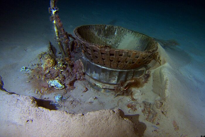 An old rusty rocket engine component lying at the bottom of the ocean