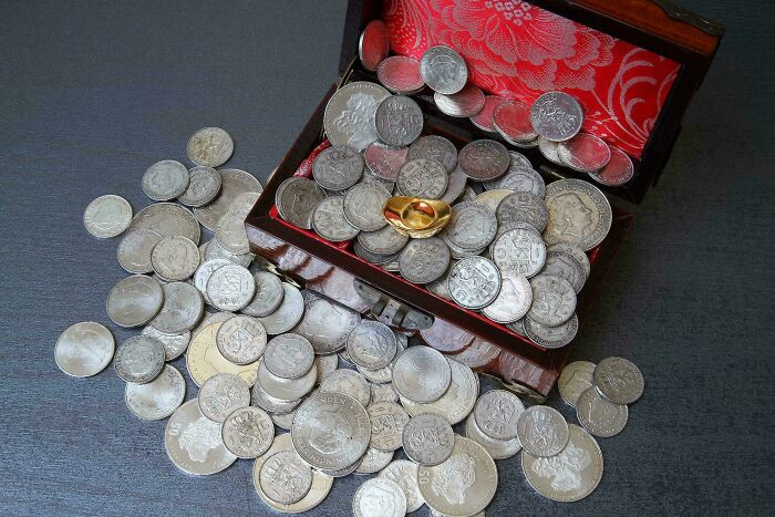 An open chest filled with silver coins representing treasure discovered at the bottom of the ocean
