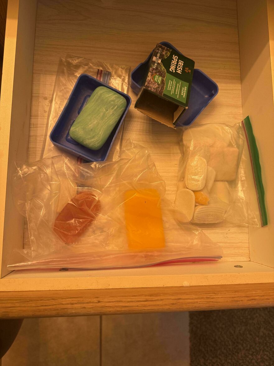 Drawer with leftover soap bars and toiletries in a rustic cabinet