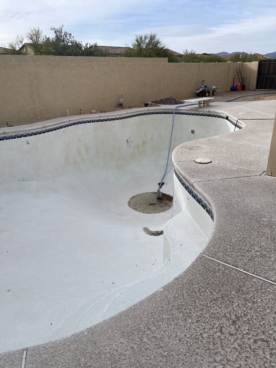 Empty backyard swimming pool with dirty surface and hose inside