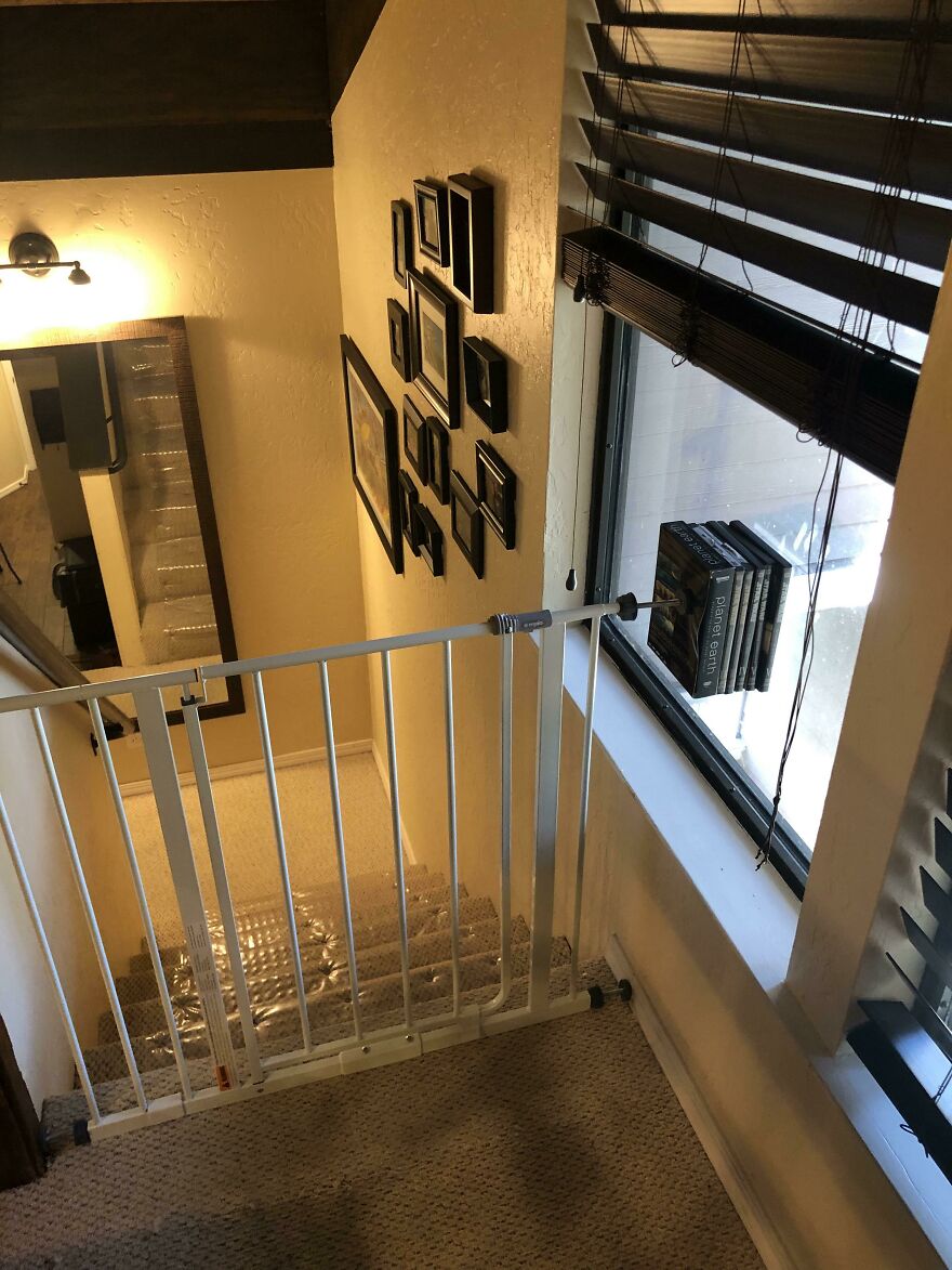 Unsafe baby gate poorly installed at top of stairs in vacation rental home