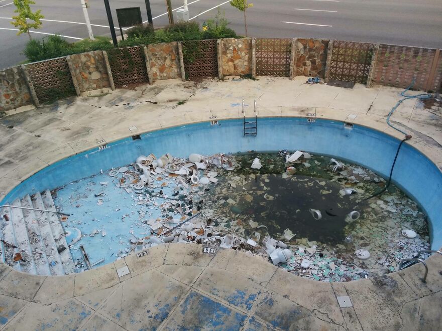 Abandoned hotel pool filled with broken glass and debris