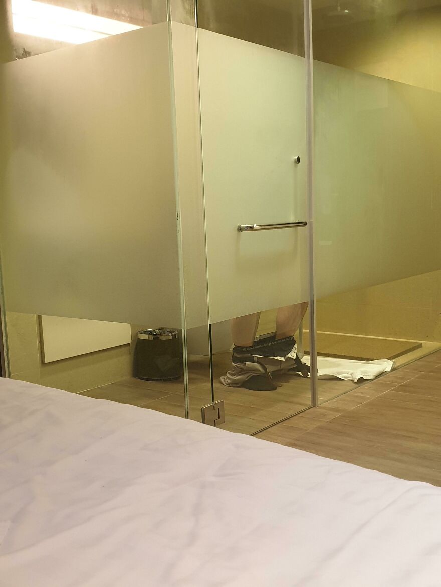 Transparent hotel bathroom wall revealing guest using toilet in Airbnb fail