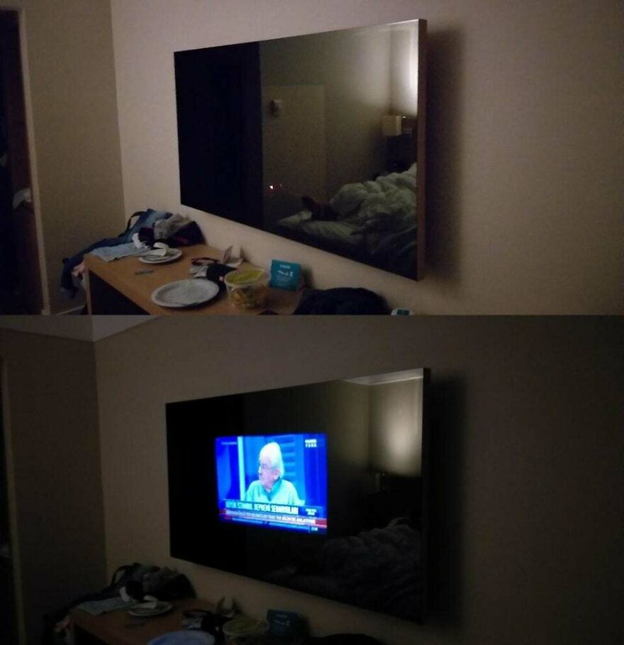 TV screen is a mirror in a dim hotel room with cluttered desk