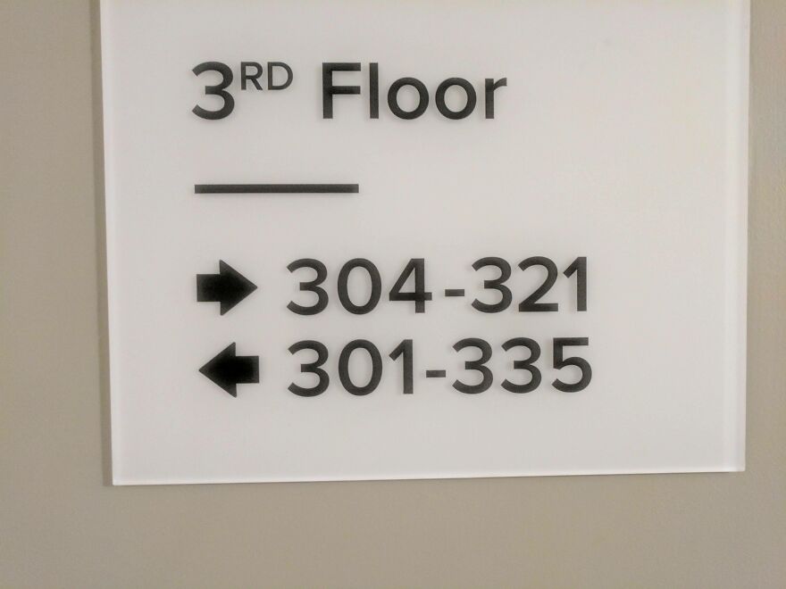 Confusing hotel floor sign showing room numbers with contradictory directions