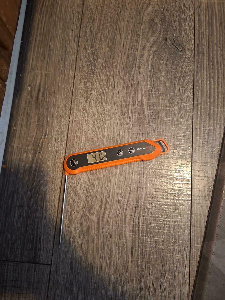 Digital thermometer placed on wooden floor showing 41.2 degrees hotel Airbnb fail