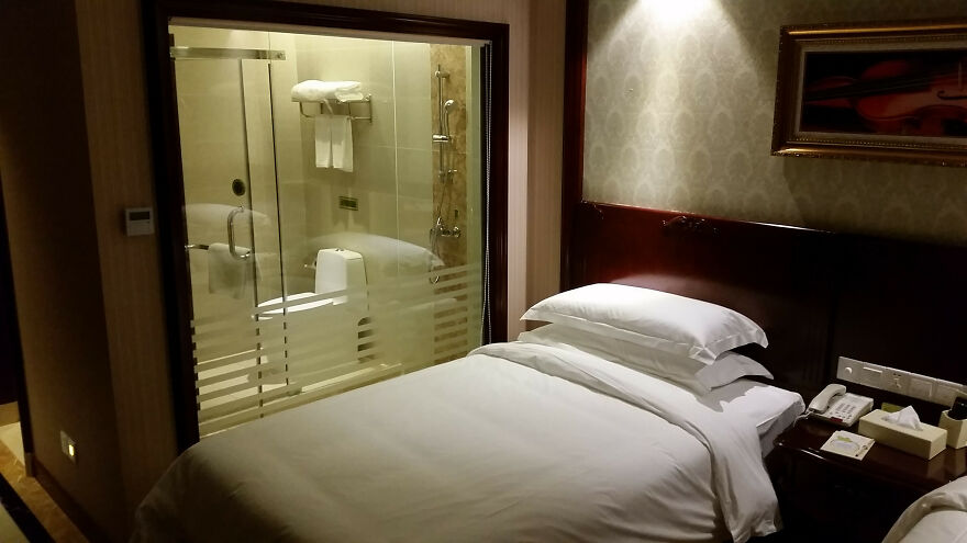 Hotel room with transparent bathroom wall showing toilet and shower