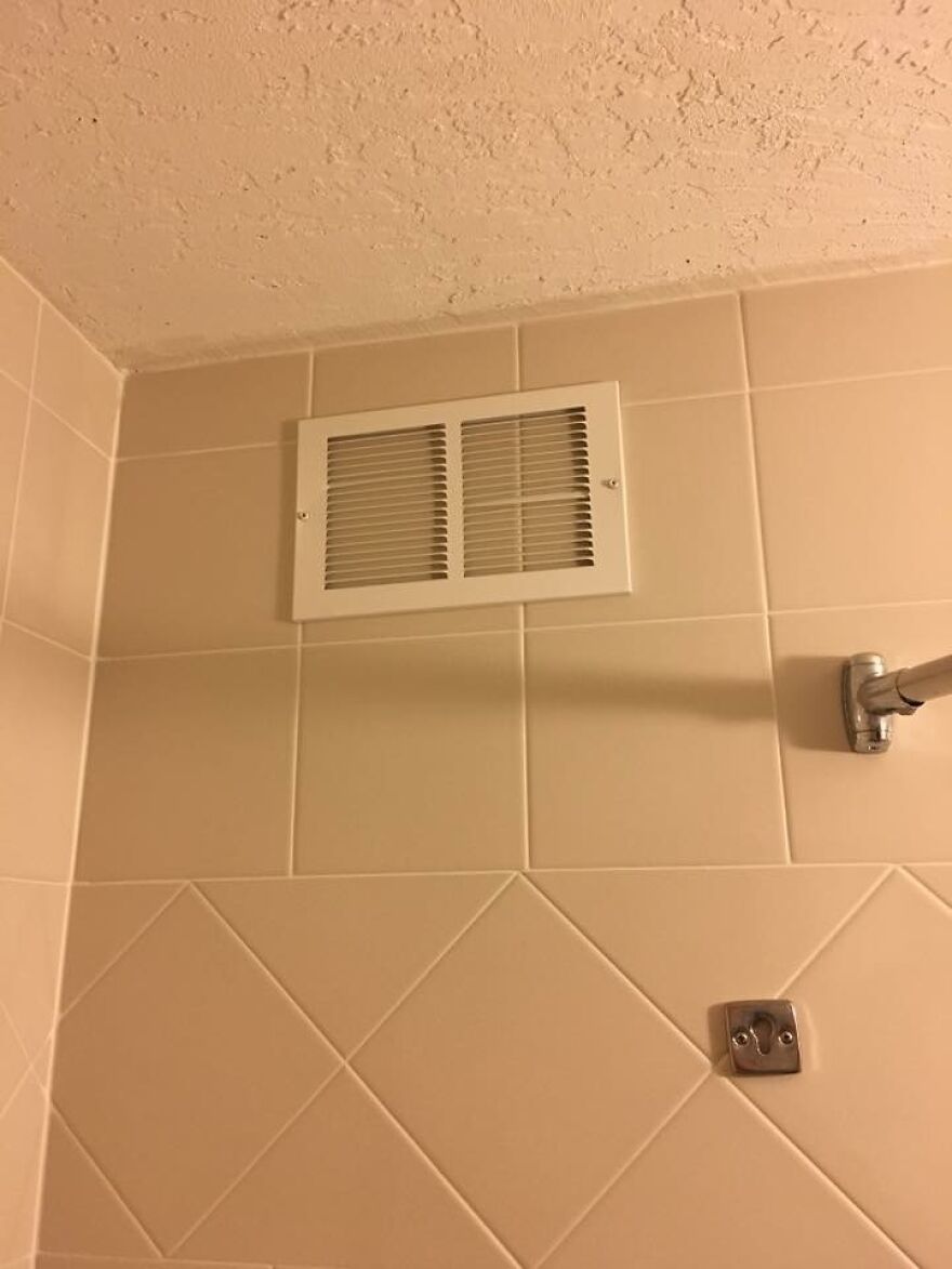 Bathroom wall with misplaced vent near shower curtain rod hotel fail
