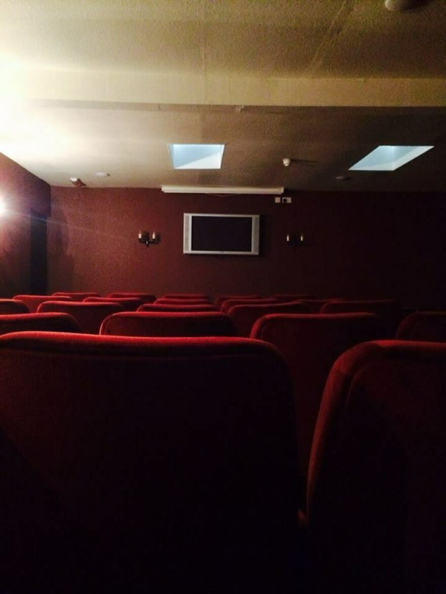 Small hotel room theater with red seats and a TV on the wall